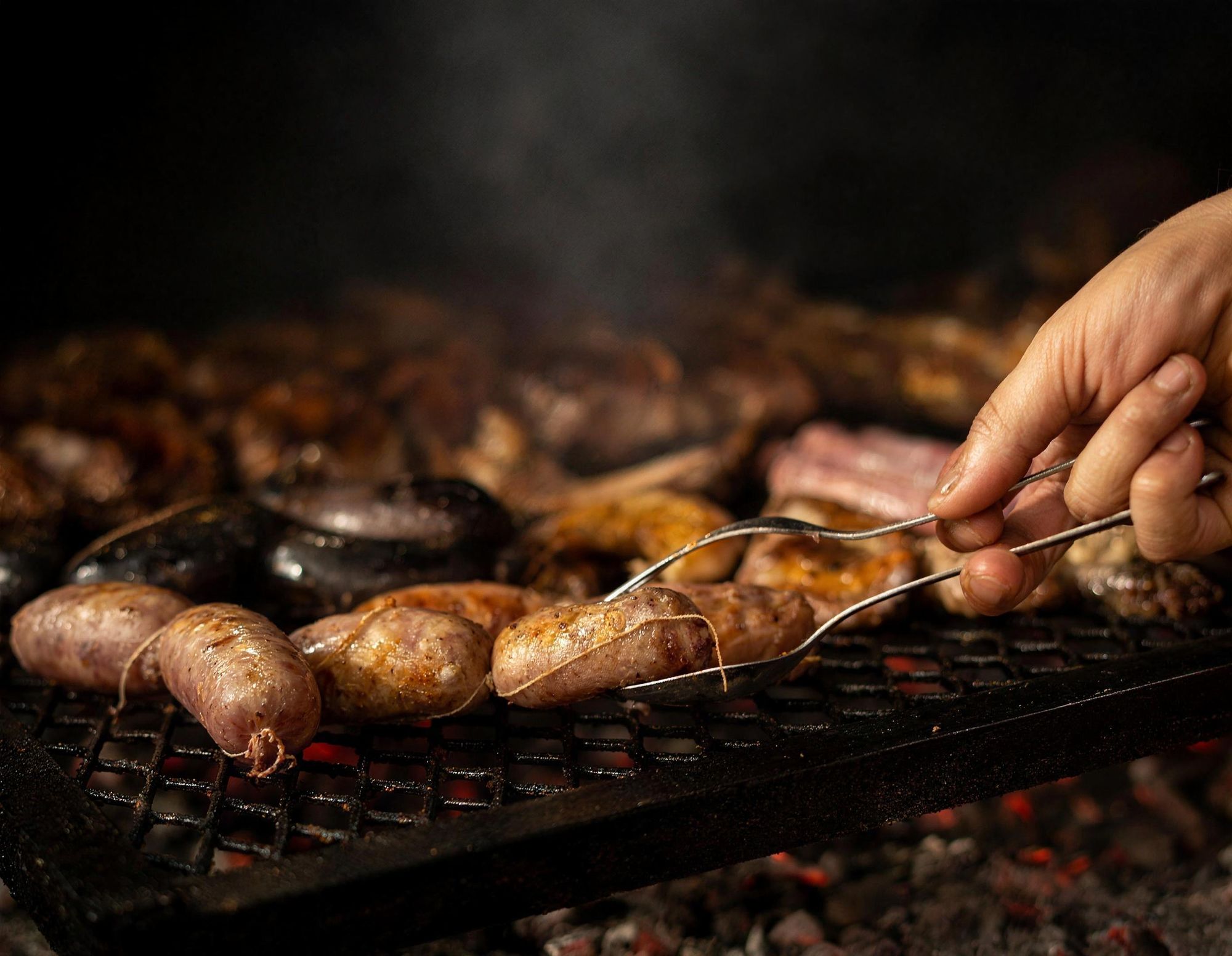 Chorizos, morcillas y achuras dorándose sobre las brasas